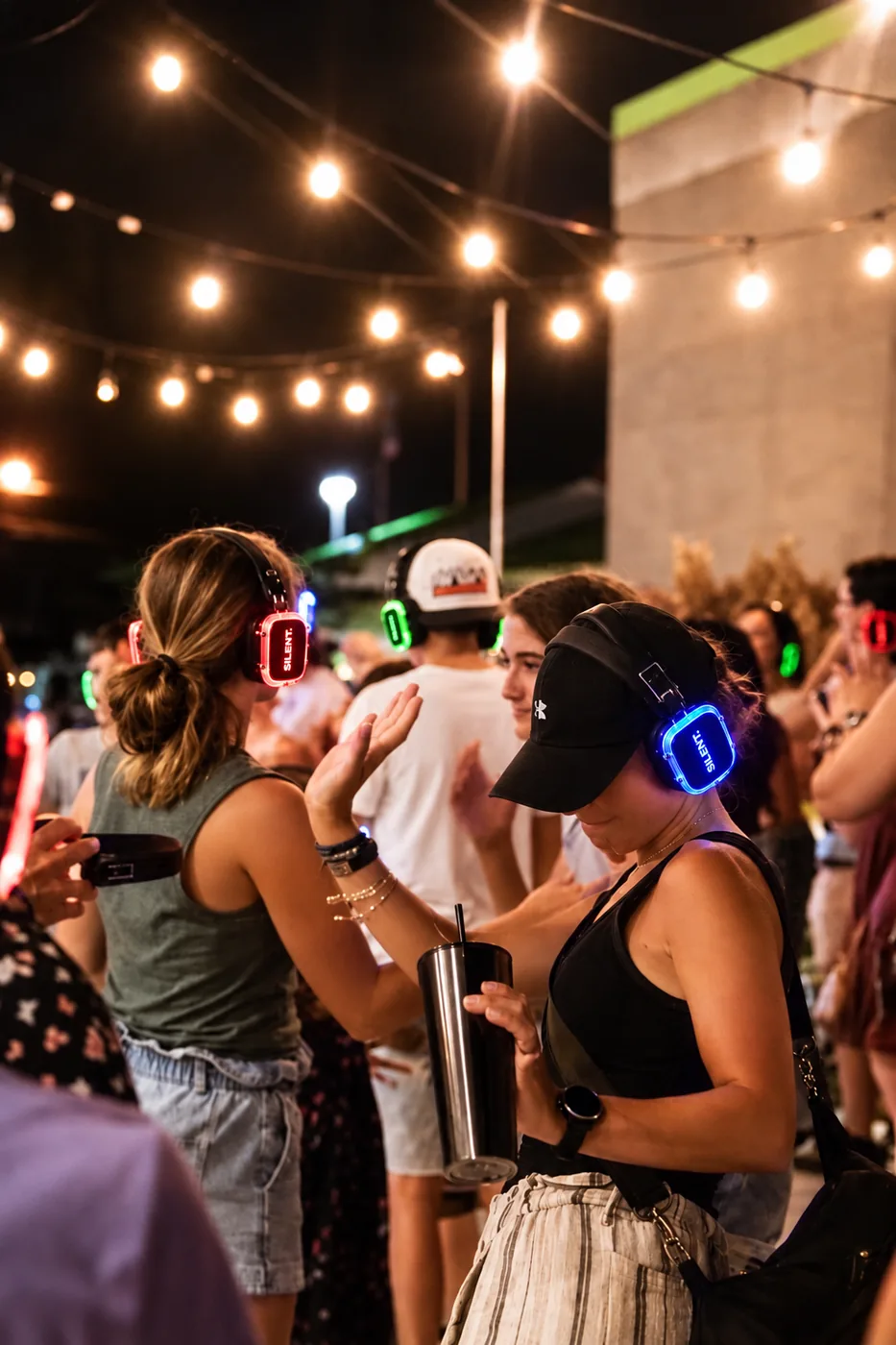 Друзі в навушниках Silent Disco під гірляндами на вечірці просто неба