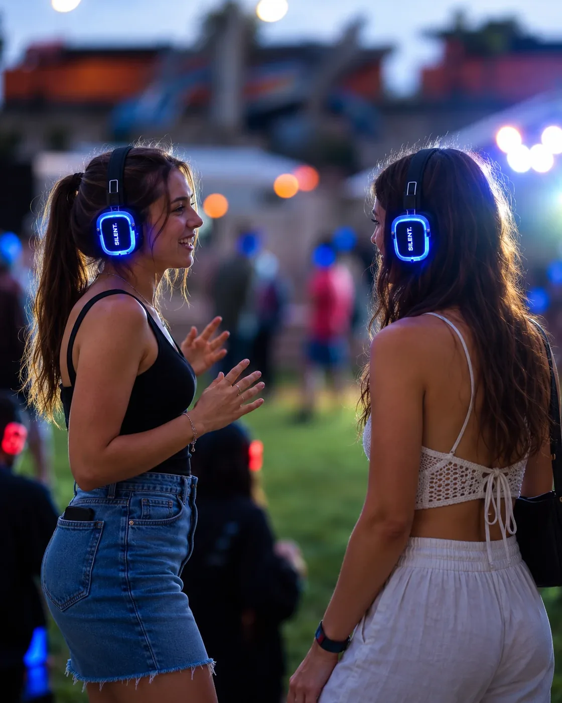 Дві дівчини розмовляють у парку в навушниках Silent Disco